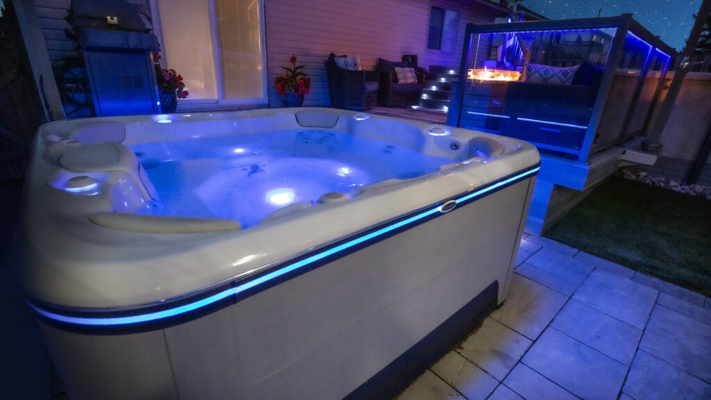 Close up of a corner of a hot tub with a glow of blue lights around the side of the hot tub.